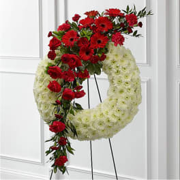 Red and white floral wreath on a stand with cascading red flowers
