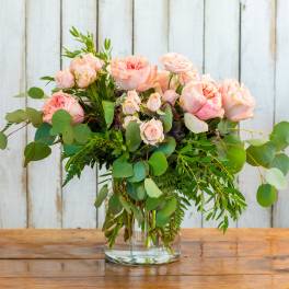 Pink roses in a clear glass vase with eucalyptus