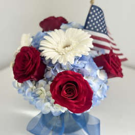 Red roses and white daisy bouquet with a small American flag