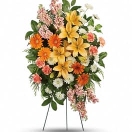 Standing floral spray with yellow lilies, orange daisies, and pink flowers
