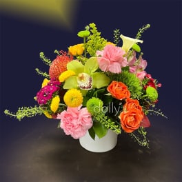 Colorful mixed flower arrangement in a white vase with pink, orange, yellow, and green blooms