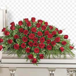 Red rose casket spray with greenery on a white casket