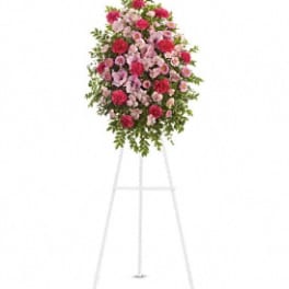 Standing floral spray of pink and red flowers on a white easel
