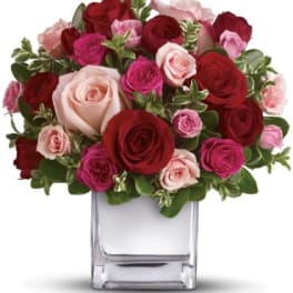 Bouquet of red and pink roses in a clear square vase