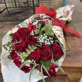 Bouquet of red roses with baby's breath wrapped in floral paper and tied with a red ribbon