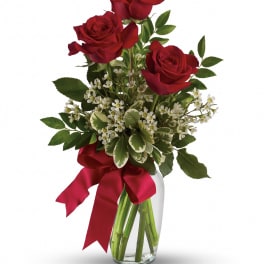 Red roses in a clear glass vase with a red ribbon