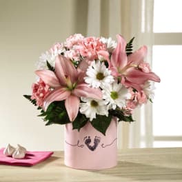 Pink lilies and white daisies in a pink vase with a baby footprint design