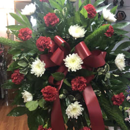 Large standing spray with red carnations and white chrysanthemums tied with a burgundy ribbon
