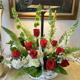 Basket arrangement of red roses and white flowers with tall green spikes