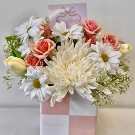 Pink and white flower arrangement in a checkered gift box