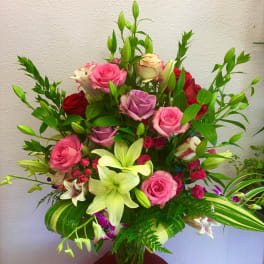 Mixed bouquet of pink and red roses with lilies in a glass vase