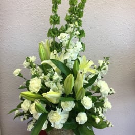 White floral arrangement with lilies and carnations in a textured vase