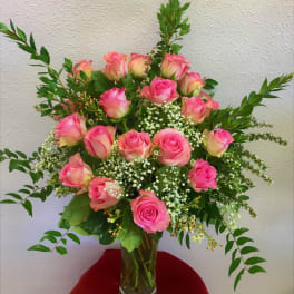 Pink roses arranged in a clear glass vase with white filler flowers