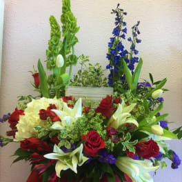 Large mixed floral arrangement with red roses, white lilies, and blue delphinium