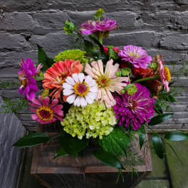 Colorful mixed bouquet of zinnias and hydrangea in a rustic container