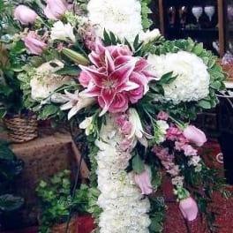 Large pink and white floral cross arrangement with lilies and hydrangeas