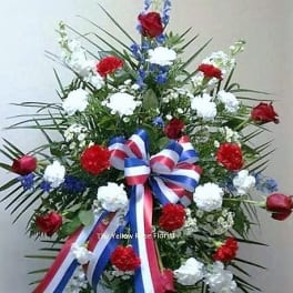 Standing floral spray with red, white, and blue flowers and ribbon