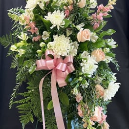 Standing floral spray with white and peach flowers and a pink ribbon