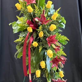 Tall floral spray with yellow roses and burgundy lilies on a stand
