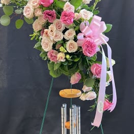 Pink and blush rose arrangement on a stand with a ribbon bow