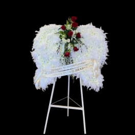 White funeral wreath with red roses on a standing easel