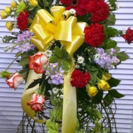 Tall standing floral spray with red, yellow, blue, and lavender blooms