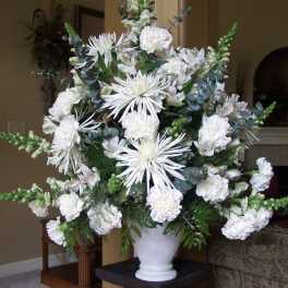 White floral arrangement in a white vase with spiky blooms and carnations