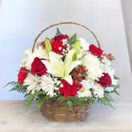 Basket arrangement of red and white flowers with a central white lily