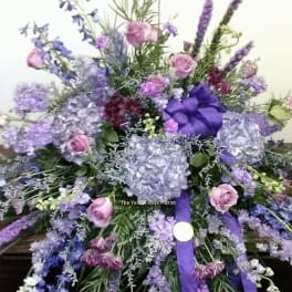 Large purple and pink floral spray with ribbon on a table