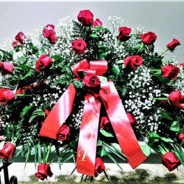 Large casket spray of red roses with pink ribbons
