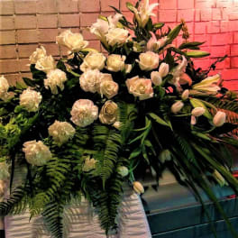Large white floral arrangement with roses, lilies, and carnations