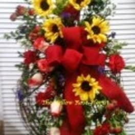 Standing floral spray with sunflowers and red roses on a white easel