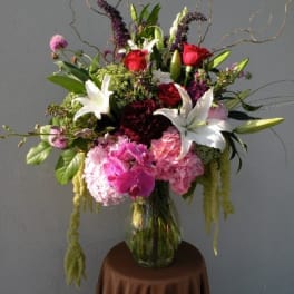 Tall mixed bouquet in a glass vase with white lilies, pink roses, and hydrangeas