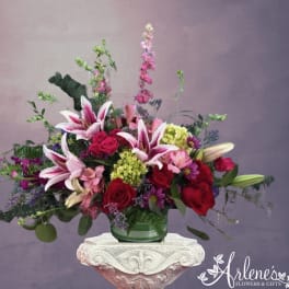 Pink lilies and red roses in a green glass vase