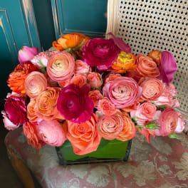 Mixed bouquet of pink, coral, orange, and magenta flowers in a green vase
