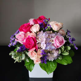 Pink and lavender rose bouquet in a white square vase