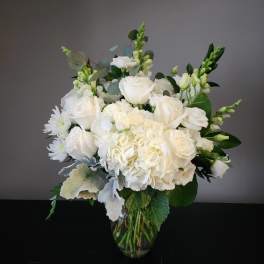 White roses and hydrangeas in a clear glass vase