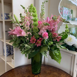 Pink lilies and snapdragons in a tall green vase