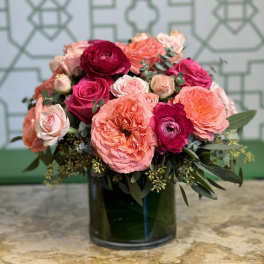 Pink and coral roses arranged in a dark glass vase