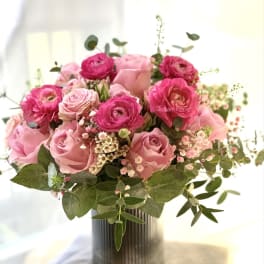 Pink roses and ranunculus in a ribbed vase