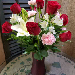 Bouquet of red roses, white lilies, and pink carnations in a vase