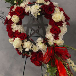 Red and white floral wreath on a black easel with a red ribbon