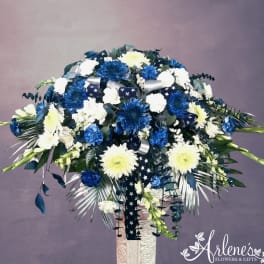 Blue and white floral spray with ribbon on a pedestal stand