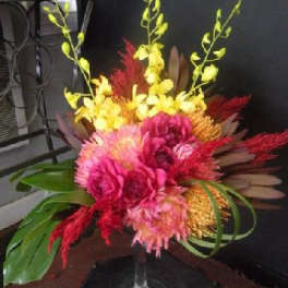 Bright tropical bouquet in a clear glass vase with pink and yellow flowers