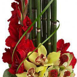 Red flowers with yellow orchids in a wooden box and bamboo stems