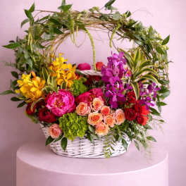 Colorful flower basket with roses and orchids in a white wicker basket
