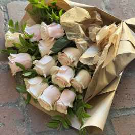 Bouquet of pale pink roses wrapped in brown paper