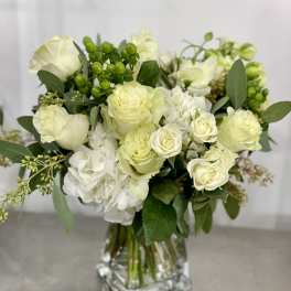 White roses and hydrangeas in a clear glass vase