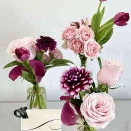 Pink rose and purple tulip arrangements in clear glass vases