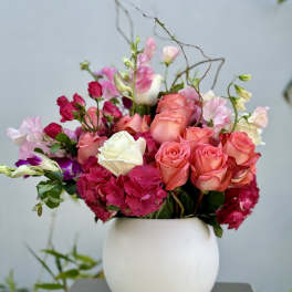 Pink and coral roses arranged in a white vase